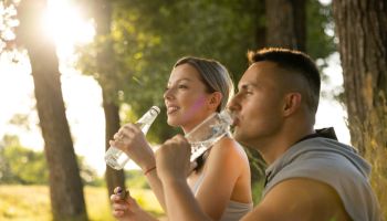 After outdoor training active couple drinking water