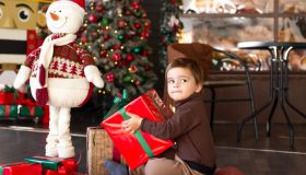 Cute toddler boy with red Christmas present at home close-up. New Year's comfort at home.