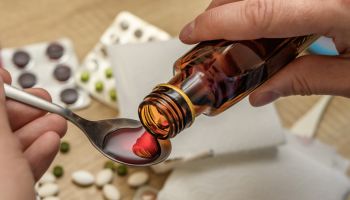 Cough syrup in a bottle poured on a spoon