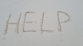 Help written on sandy beach and sea