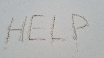 Help written on sandy beach and sea